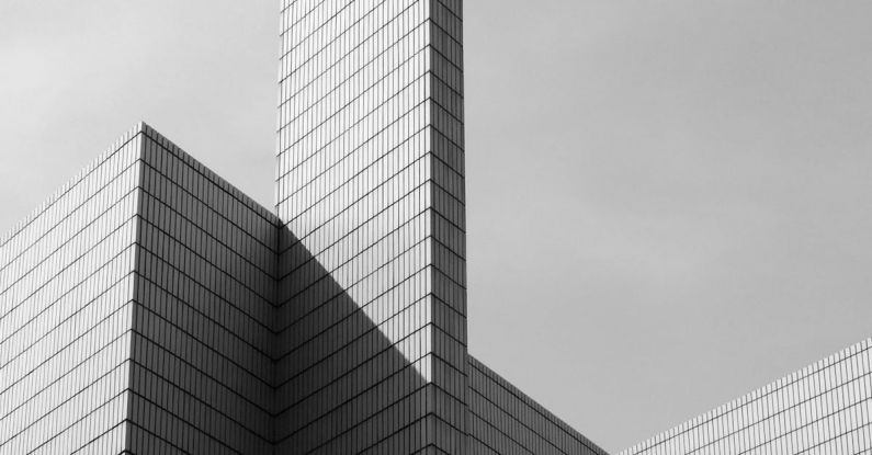 Skyscraper Design - From below black and white of contemporary geometric construction exterior with tall walls under light cloudy sky in sunny day
