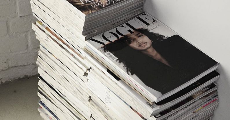 Smart Composites - High angle many fashion magazines stacked on floor against white brick wall in studio