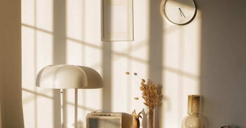 Transparent Composites - Light room with retro radio and decorative vases with dry plants on desk near wall with clock and window shadow in sunlight