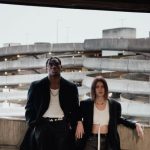 Self-healing Concrete - Full body of young confident woman and black man in trendy outfits leaning on concrete wall in multistory parking garage against urban background