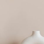 Museum Design - White ceramic vase in creative shape of ring placed on white marble stand against beige wall as home decoration element or art object