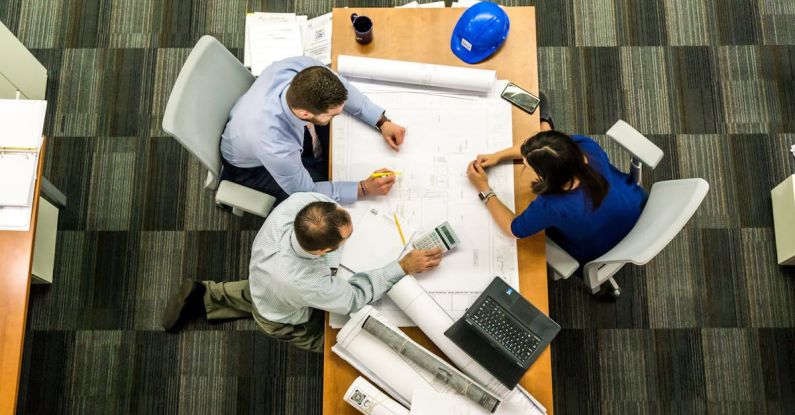 Construction Technology - Three People Sitting Beside Table